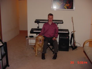 Photo of ivan and Seeing Eye dog Zeke, with two 
keyboards and a bass in the background.